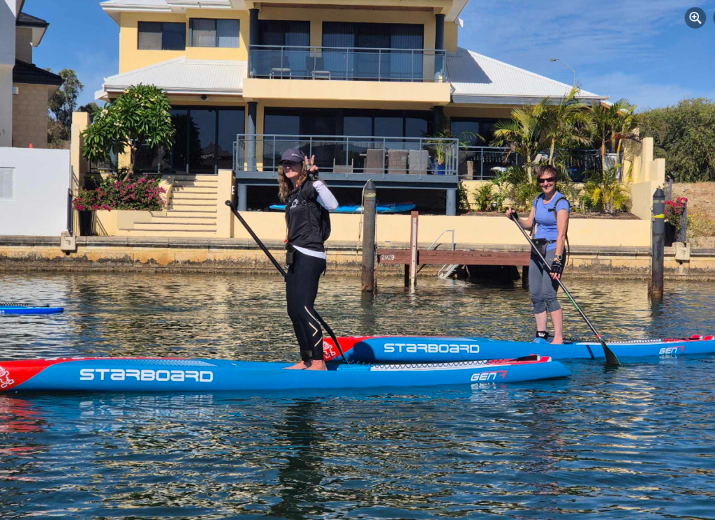 Maree from Sup Tonic with another paddler on the Swan River with a house behind her.